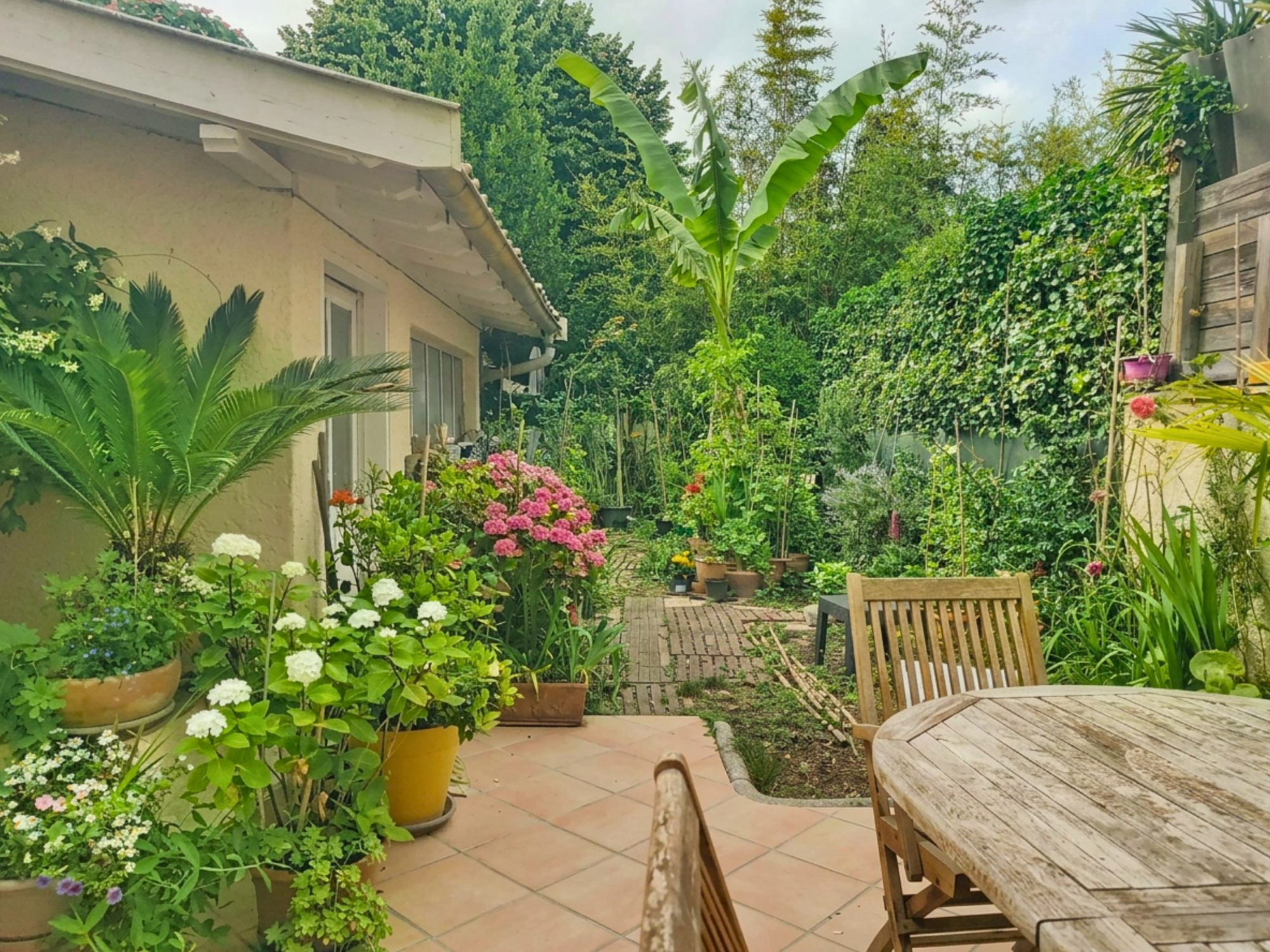 Maison individuelle avec un étage, des combles et un jardin.